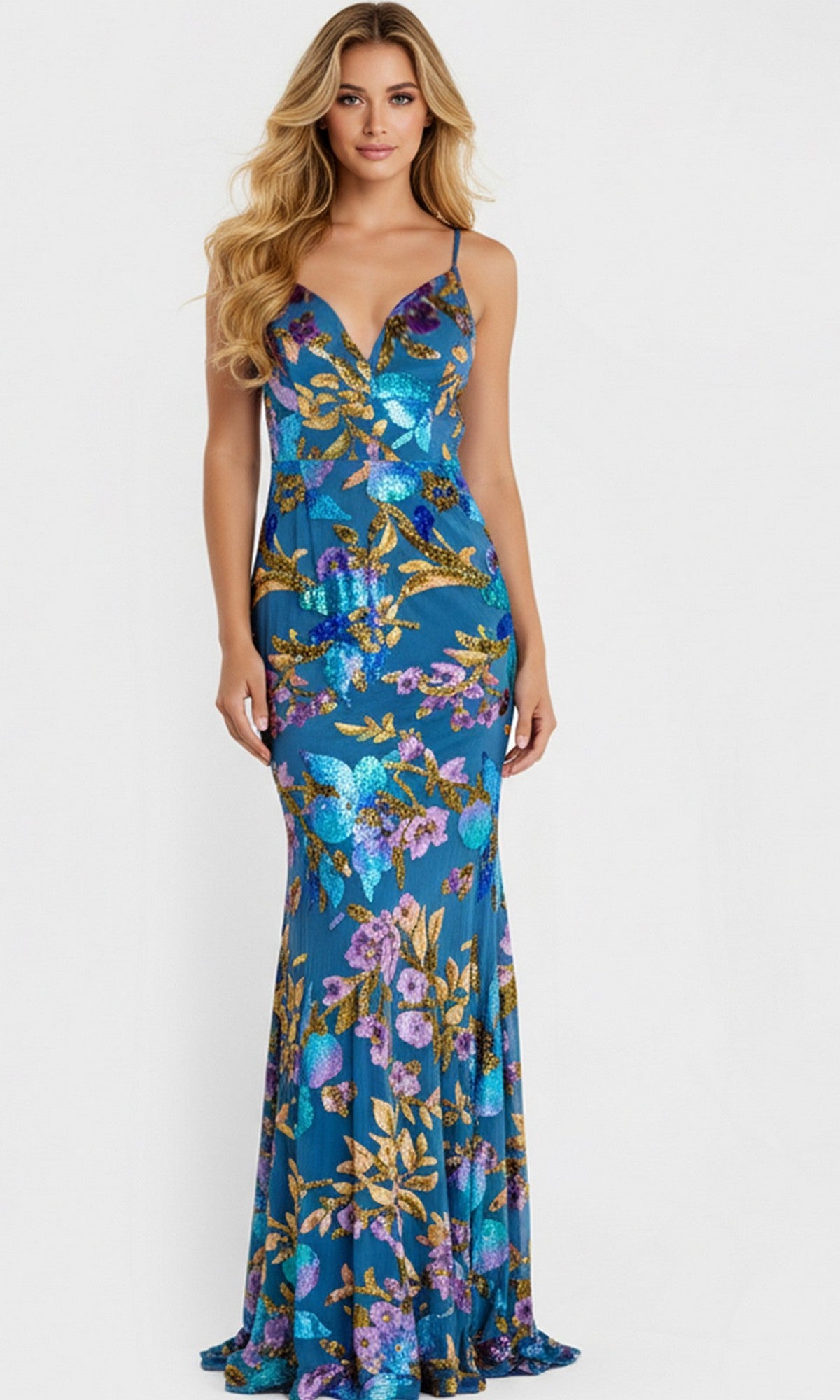 A woman models the Long Prom Dress: Jovani 47655 in Blue/Multi, a floor-length sequin gown with gold and purple floral patterns, standing against a plain white background.